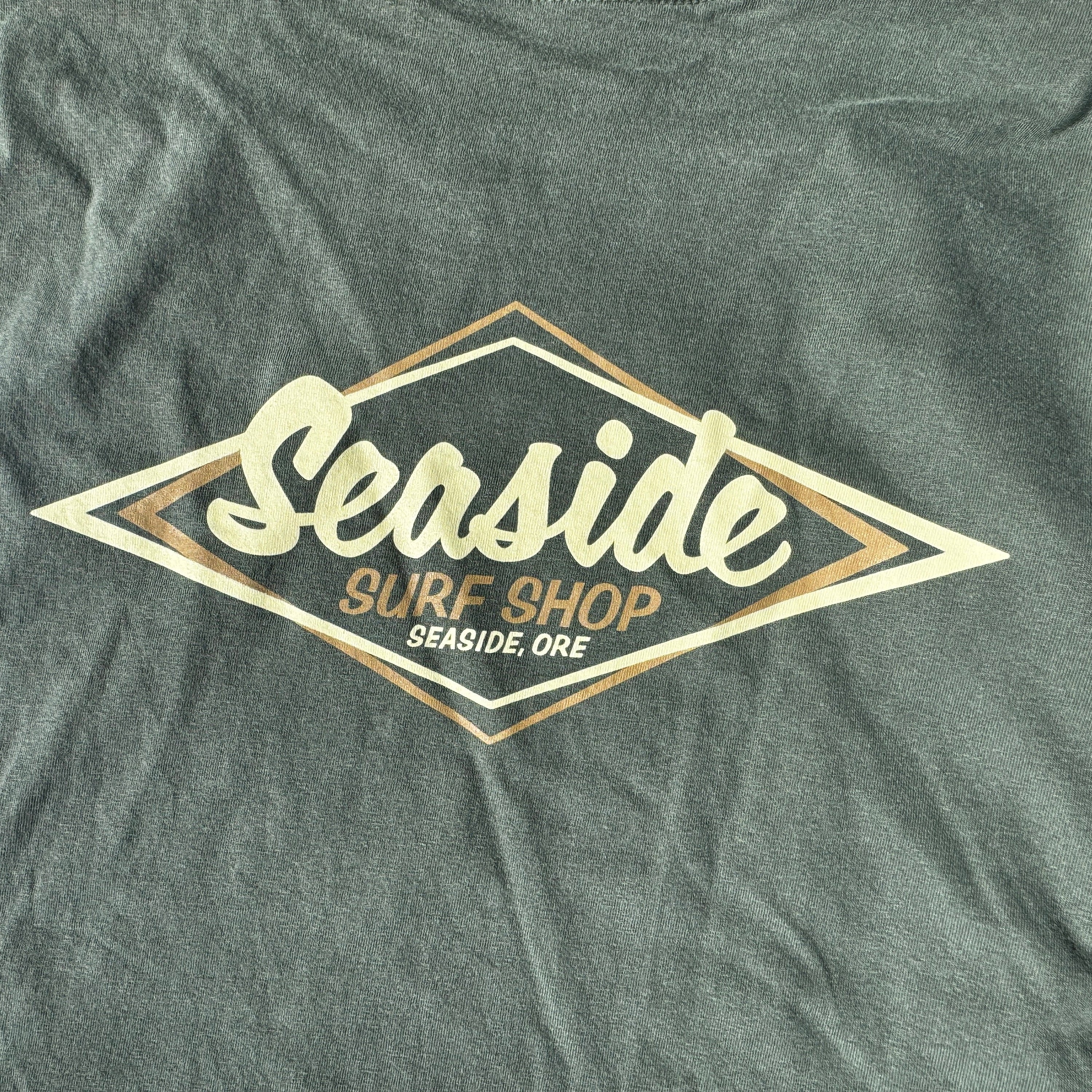 A close-up of a dark heather gray t-shirt featuring a large diamond-shaped graphic on the chest. The graphic has a cream-colored script reading &